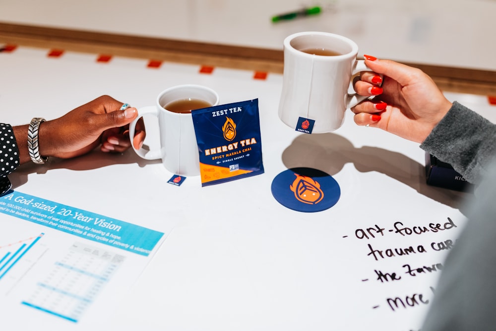 a couple of people sitting at a table with cups of coffee