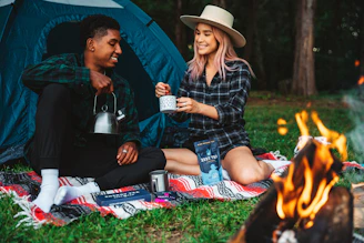 a man and a woman sitting next to a campfire