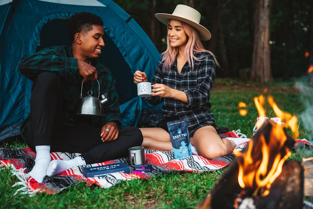 a man and a woman sitting next to a campfire