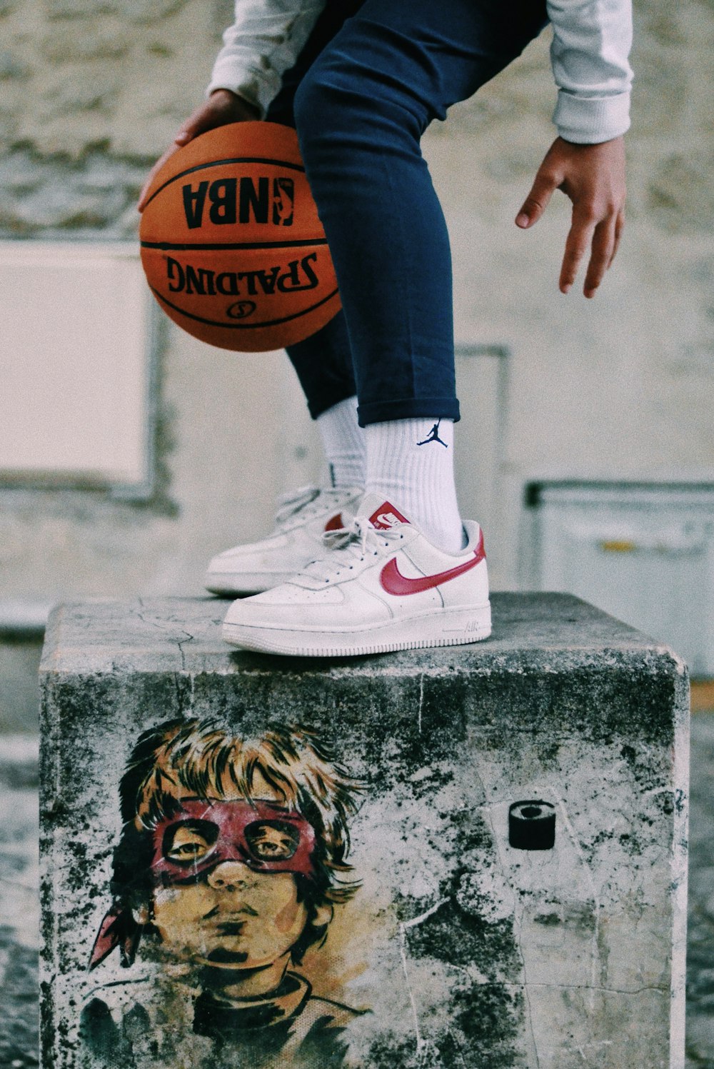 uma pessoa com uma bola de basquete sentada em cima de um bloco de cimento