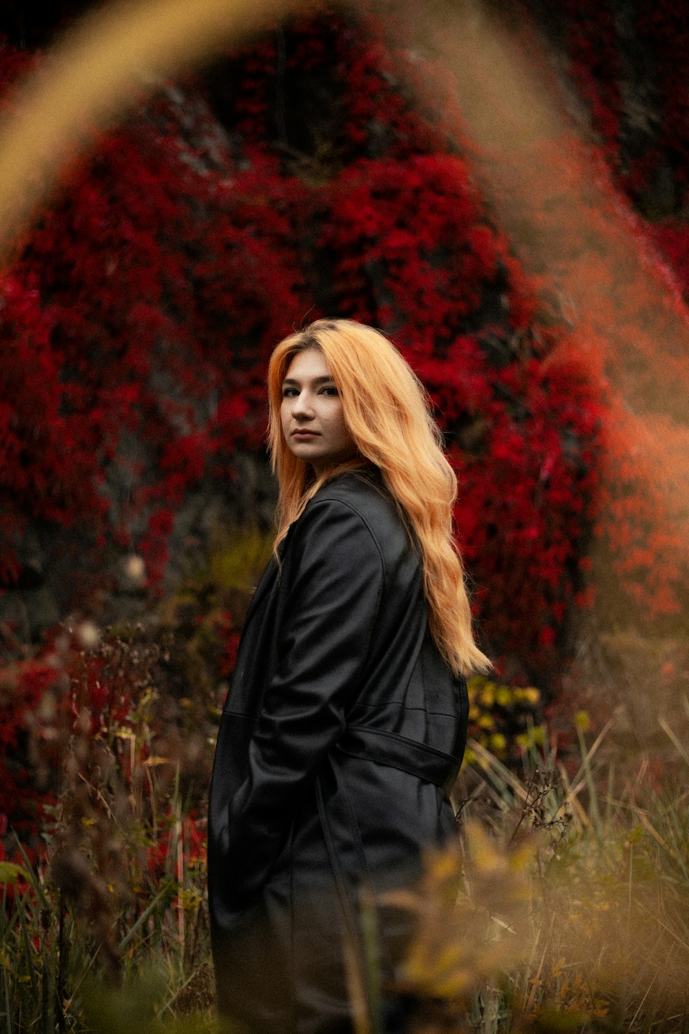 a woman with long red hair standing in a field