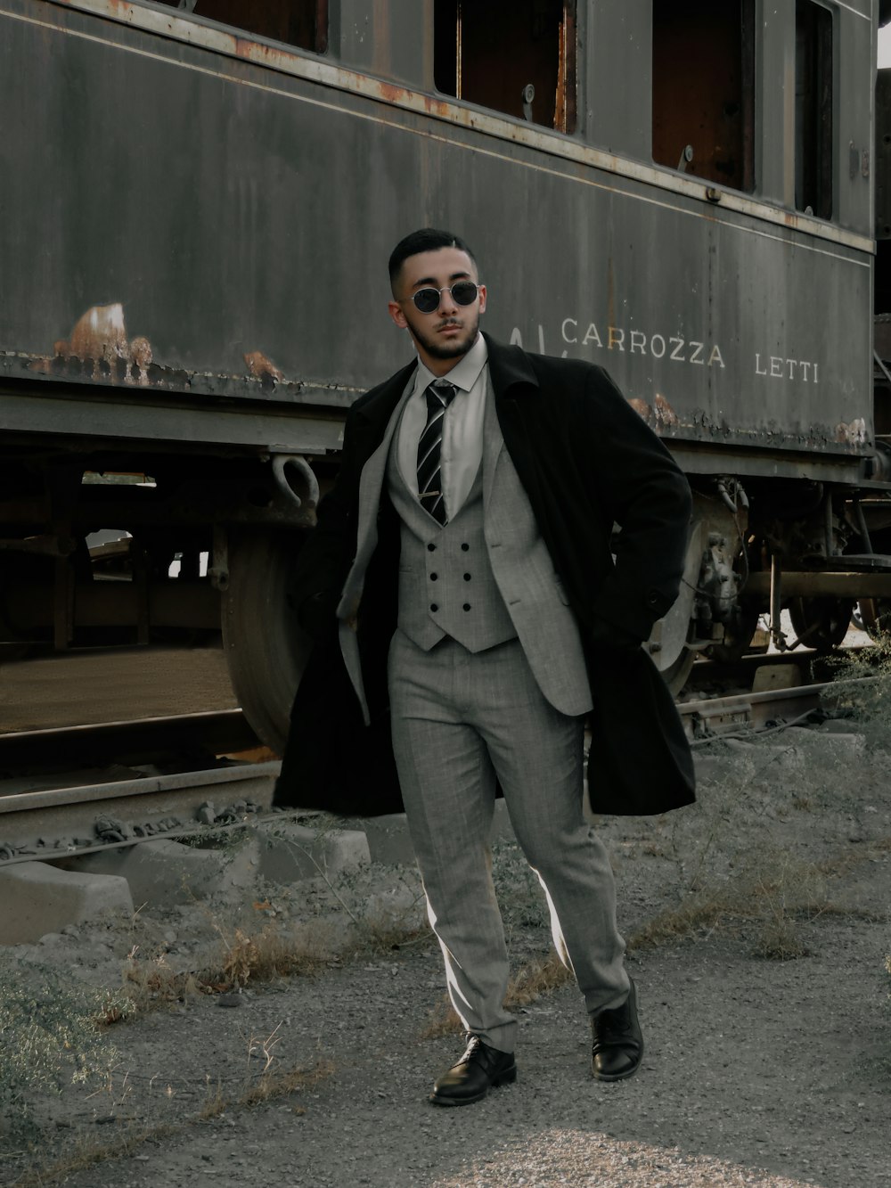 a man in a suit and tie standing in front of a train