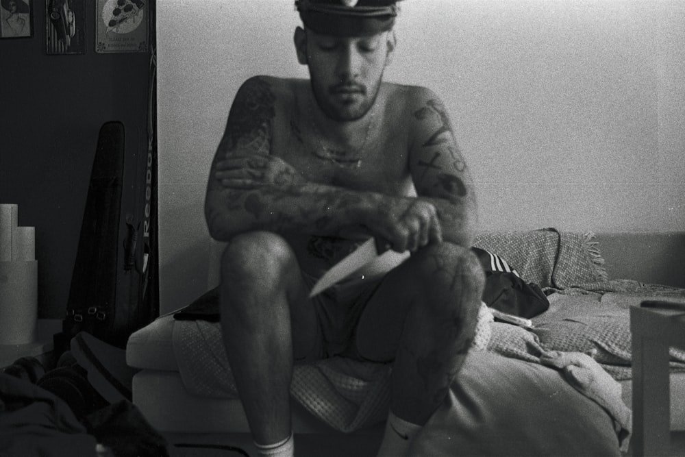 a man with tattoos sitting on a bed