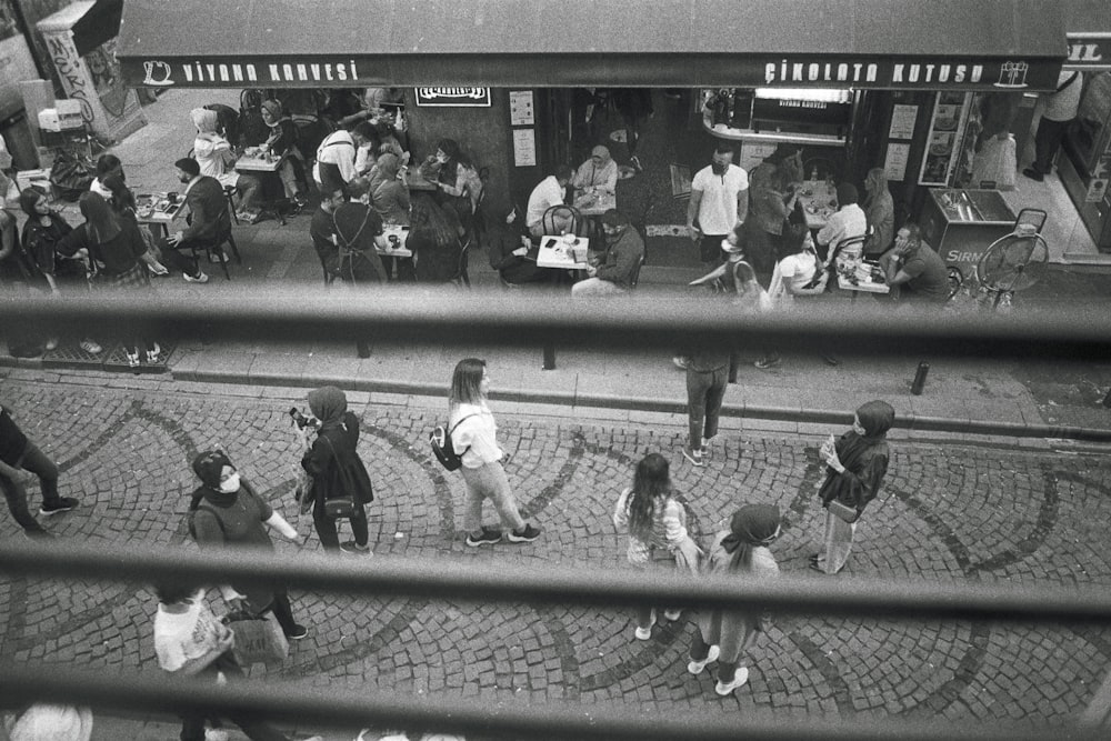 a black and white photo of people walking on a sidewalk