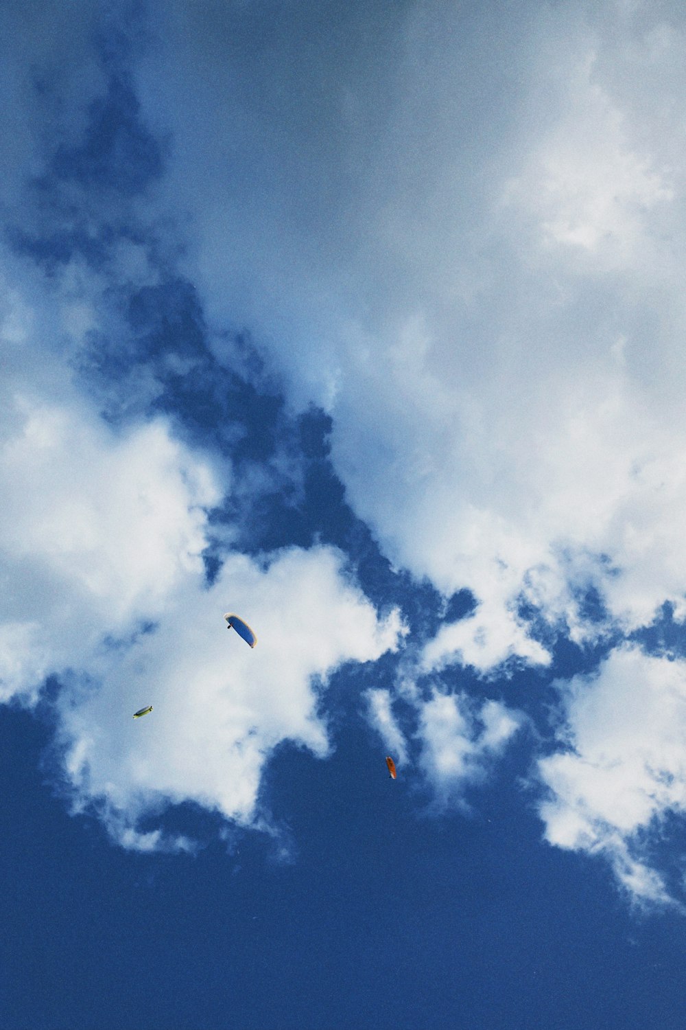 a group of kites flying through a cloudy blue sky
