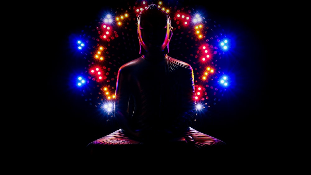 a man sitting in a lotus position with a lot of lights around him