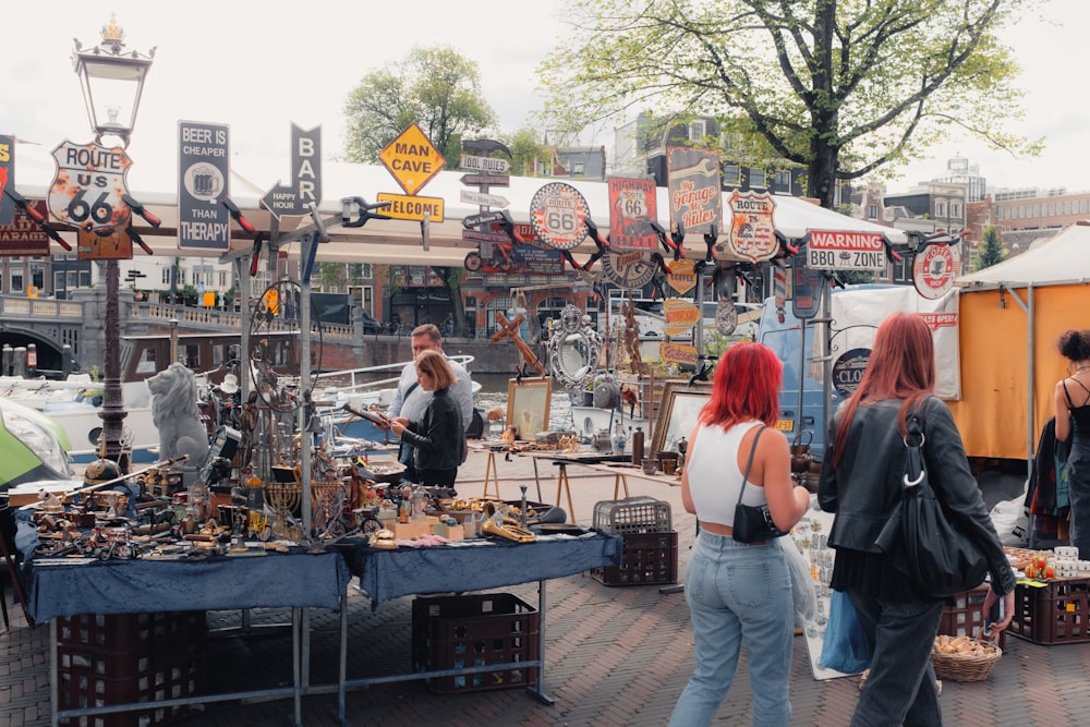 a group of people standing around a table filled with items