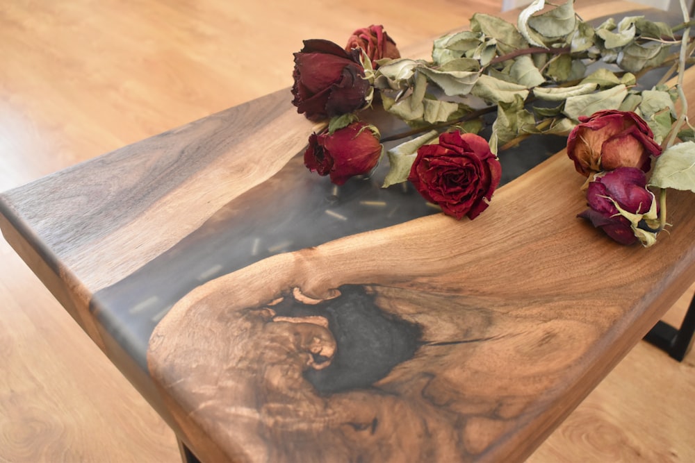 a wooden table topped with flowers on top of a hard wood floor