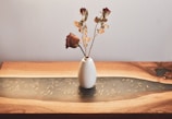 An old-fashioned ceramic vase with delicate floral patterns displayed on a wooden table.