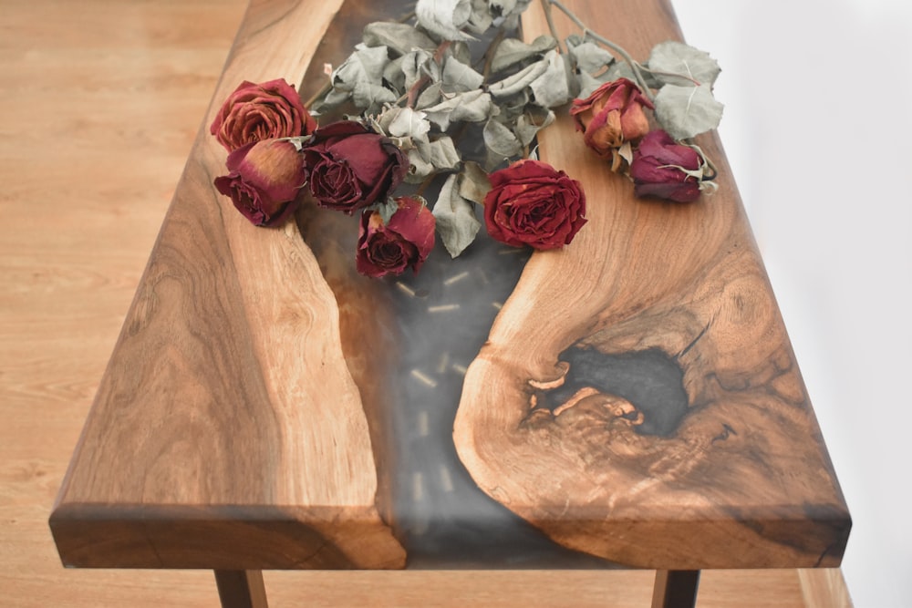 a wooden table topped with flowers on top of a wooden table