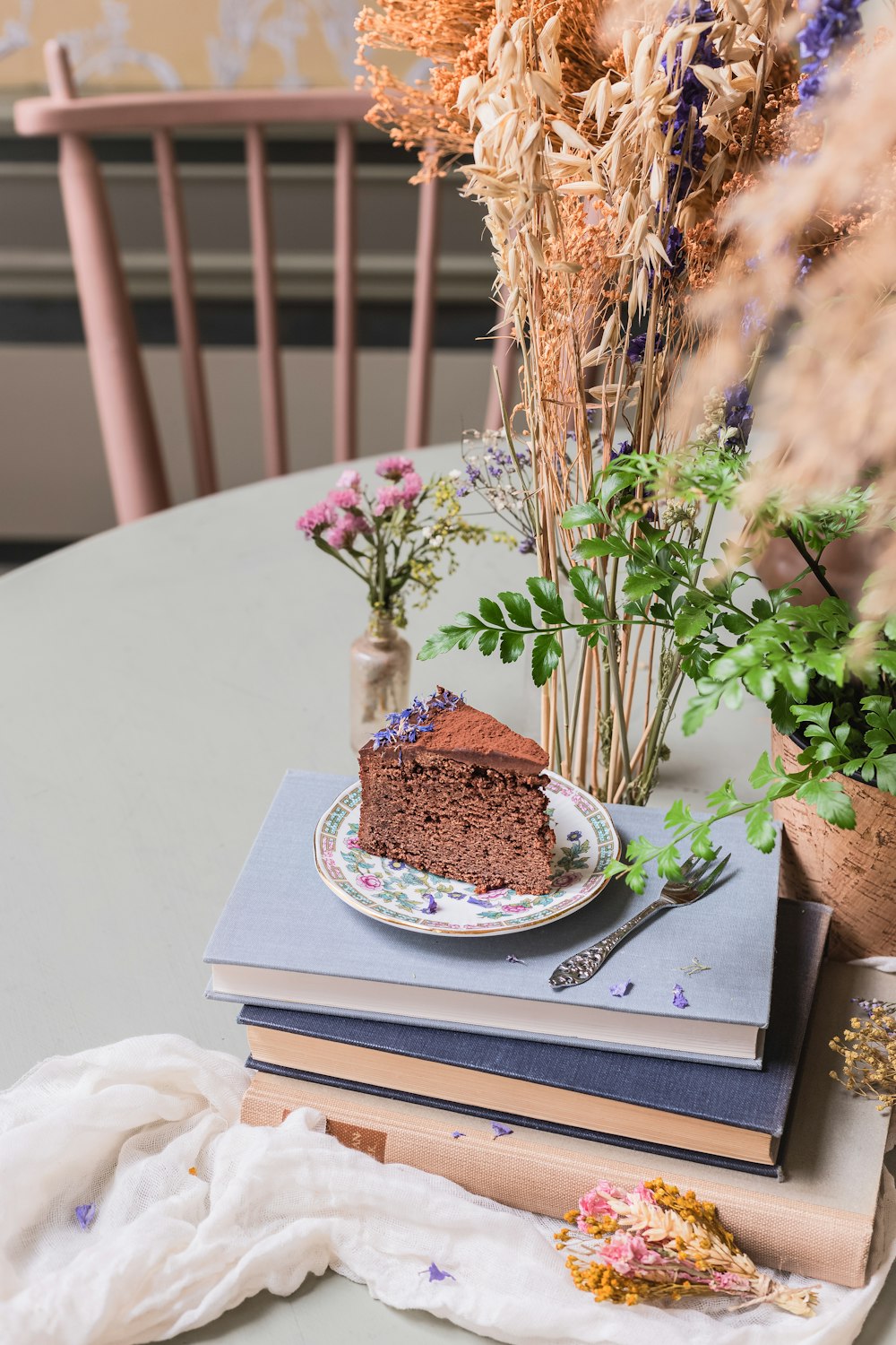 a table topped with a plate of cake and flowers