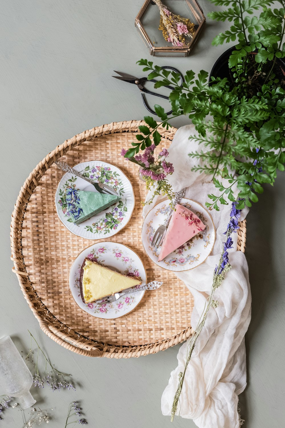 a table topped with plates of cake next to a potted plant