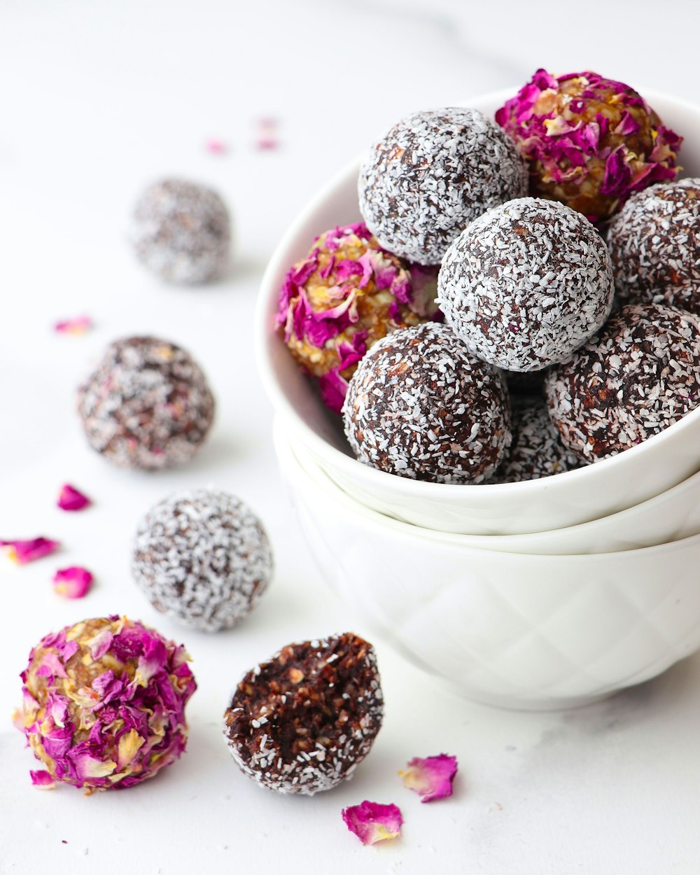 a white bowl filled with chocolate truffles covered in powdered sugar