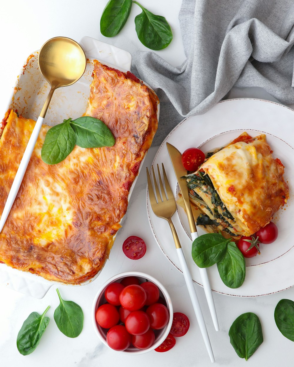 ein weißer Teller mit einer Scheibe Lasagne neben einer Schüssel