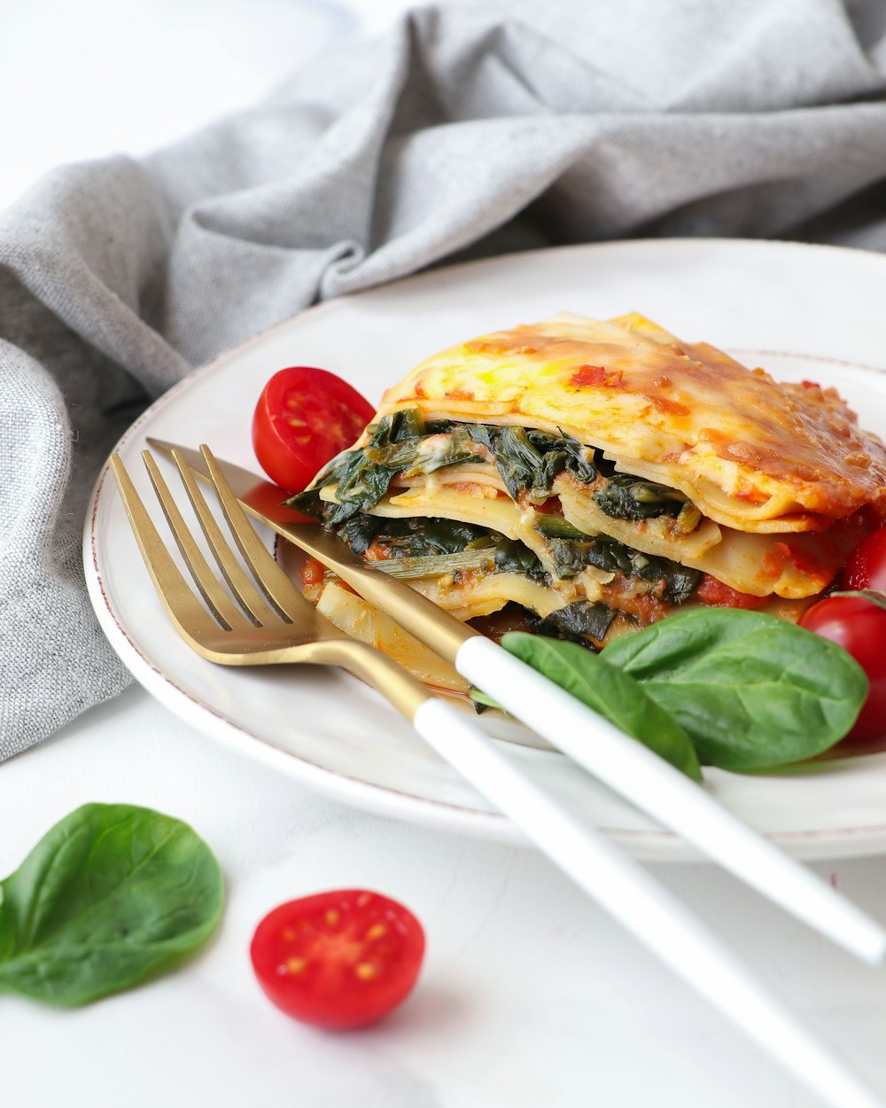 a white plate topped with lasagna covered in spinach