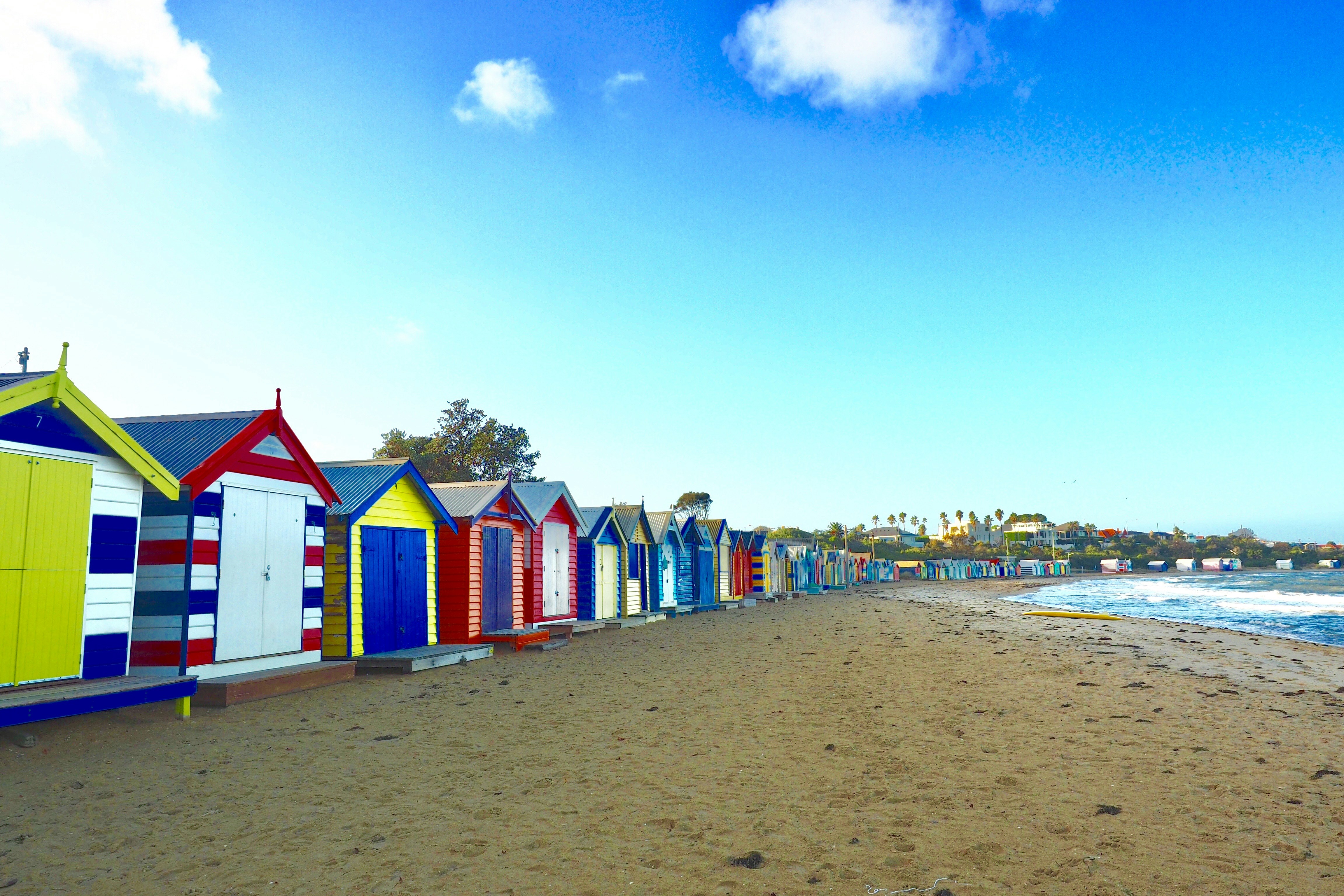 a row of colorful beach huts sitting on top of a sandy beach
