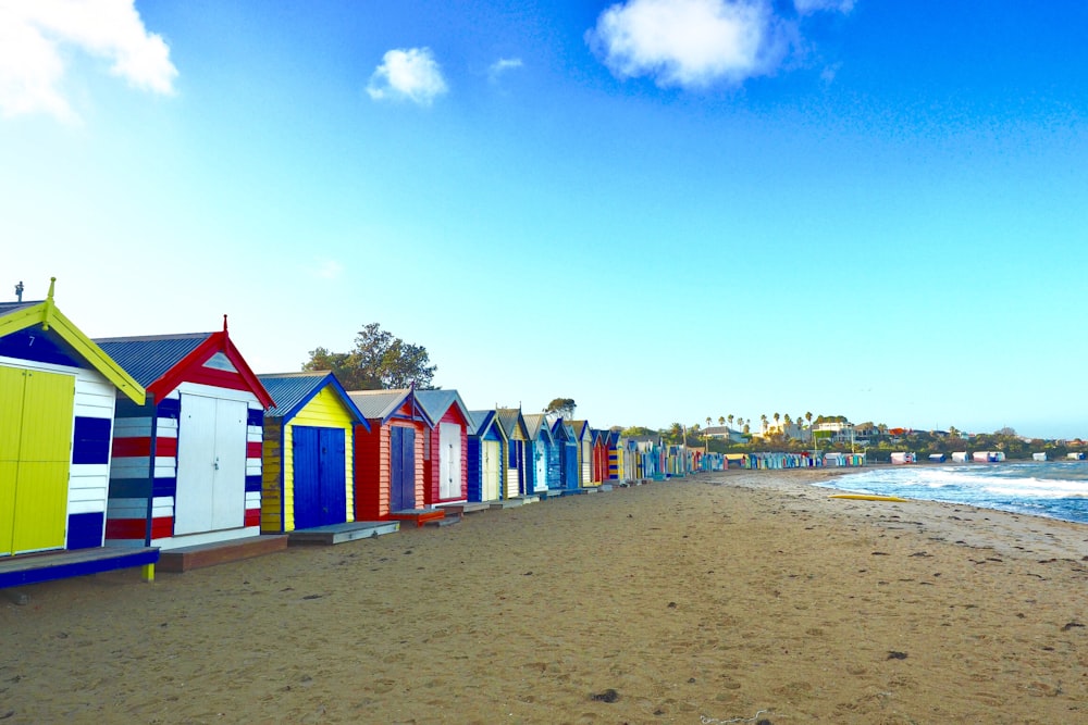 Una hilera de coloridas cabañas de playa sentadas en la parte superior de una playa de arena