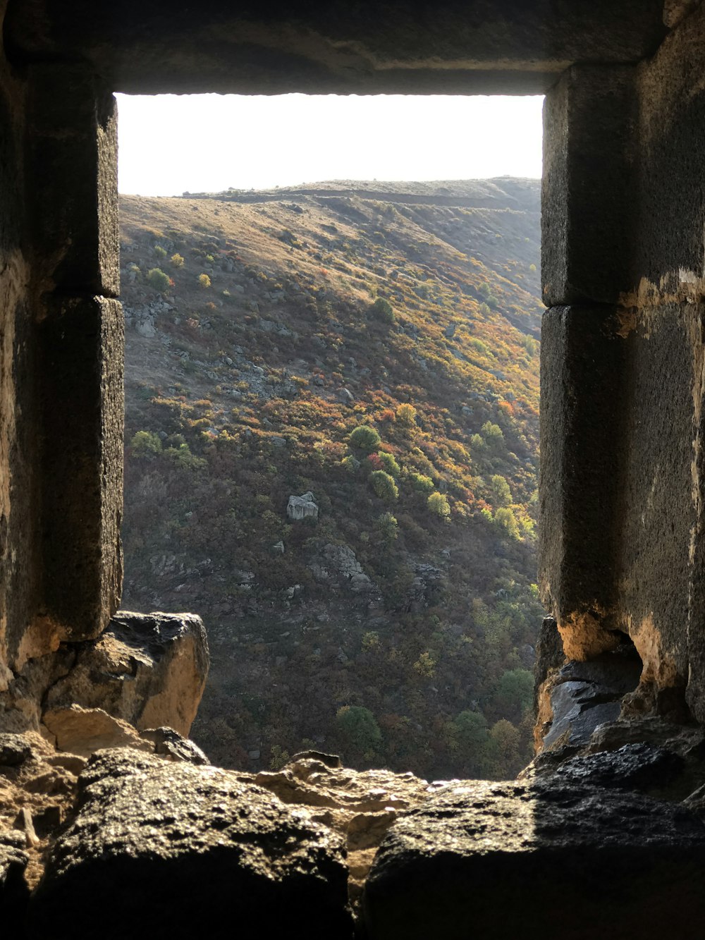 Una ventana en un edificio de piedra con vistas a un valle