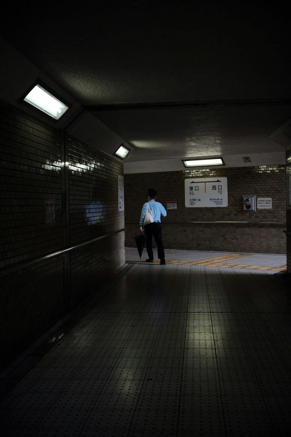 a man in a blue shirt is walking down a dark hallway