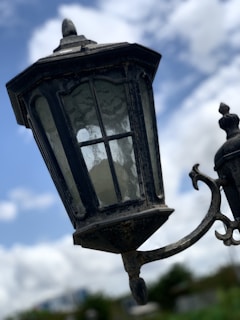 A close-up of an old lantern casting flickering light on a foggy, deserted street in the town.