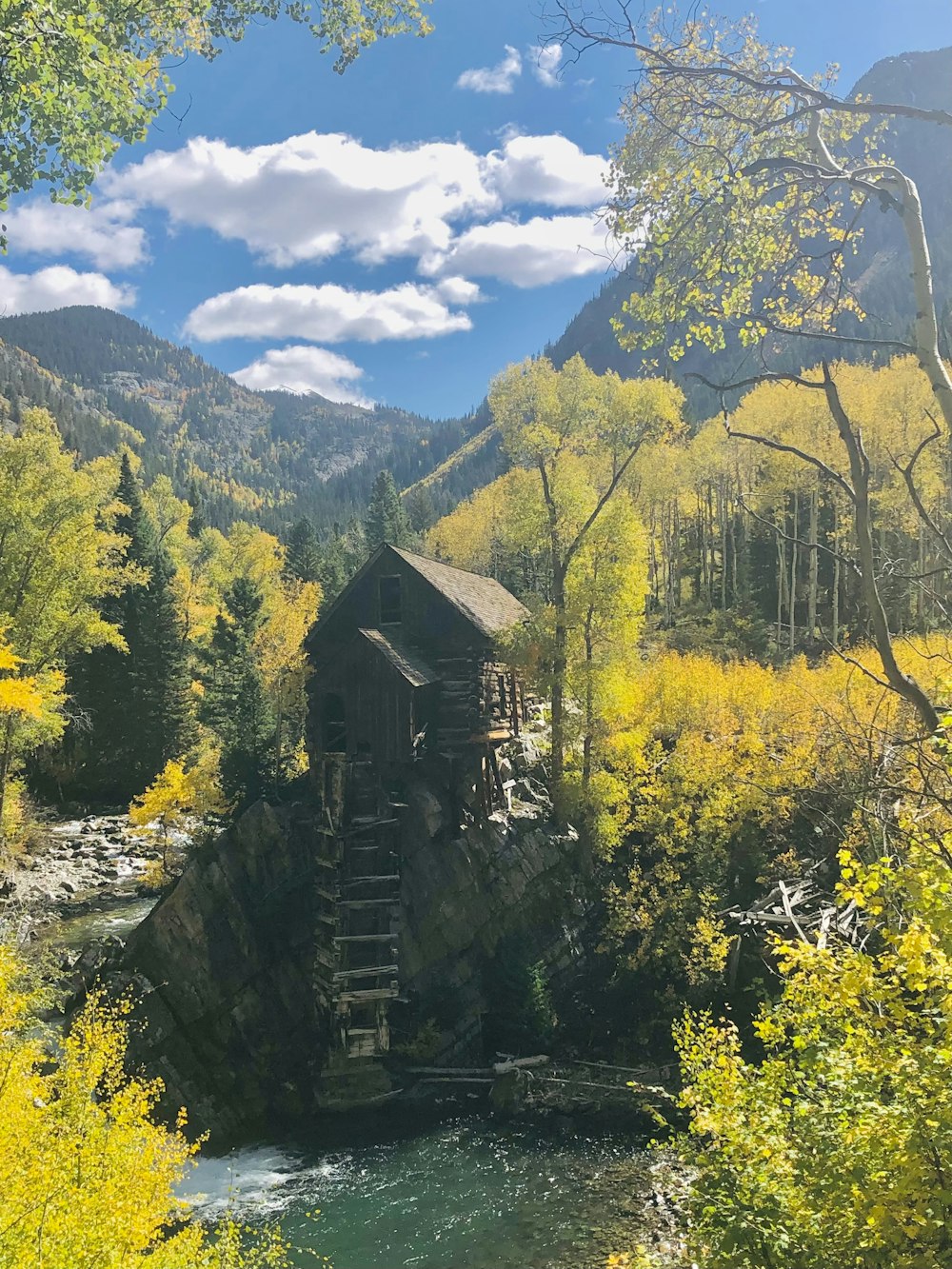 a wooden structure sitting on top of a river next to a forest