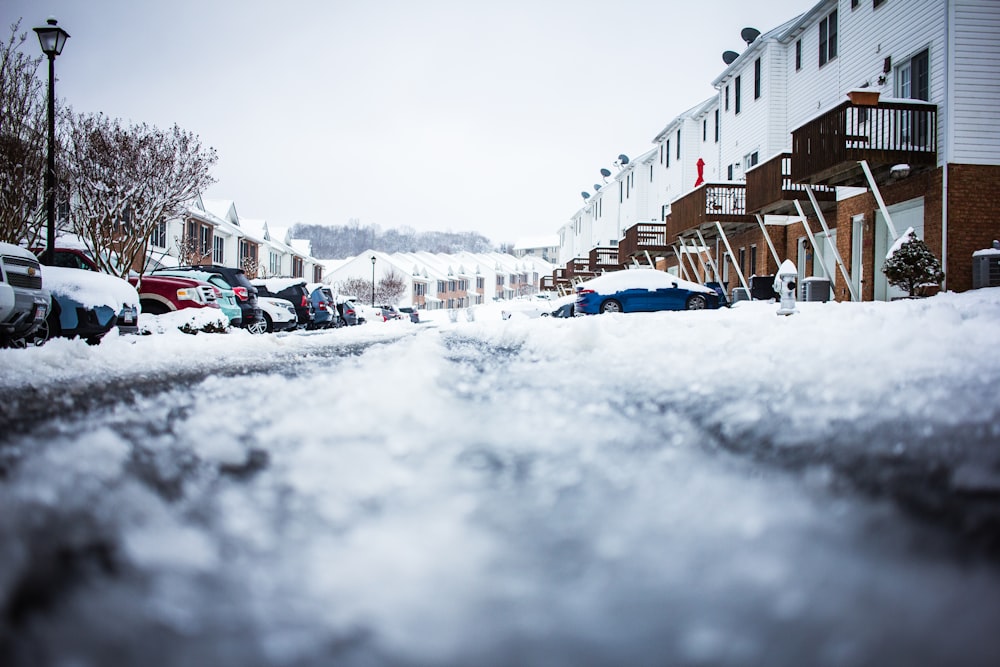 a snow covered street with cars parked on the side of it