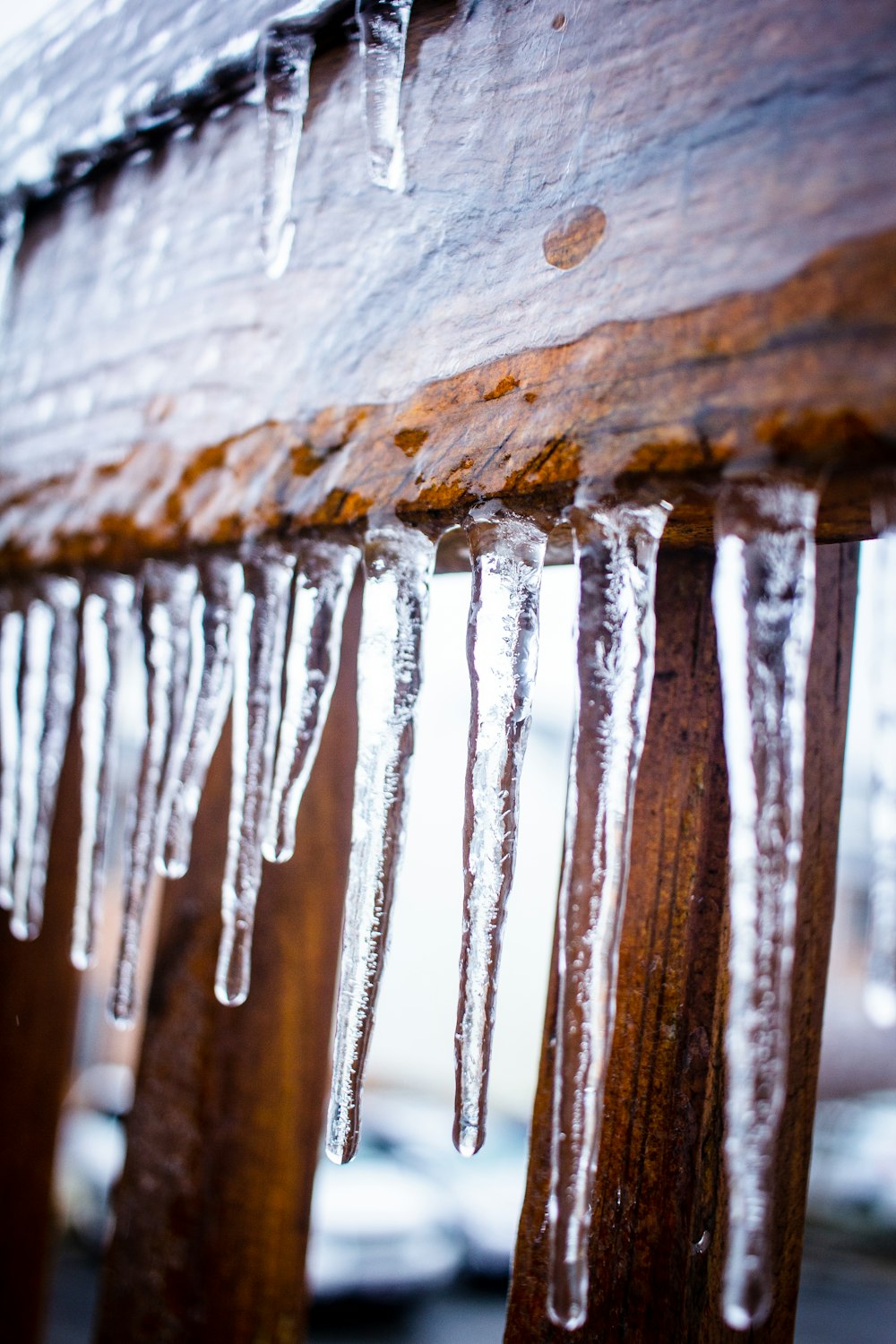 a wooden bench covered in icicles on a snowy day