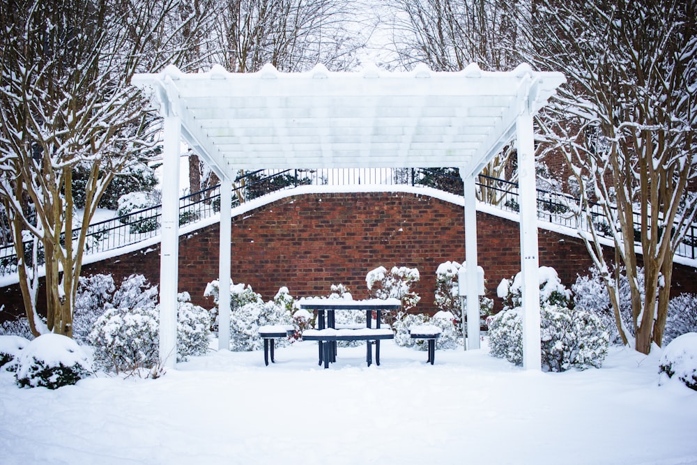 um banco de parque coberto de neve sob um dossel branco