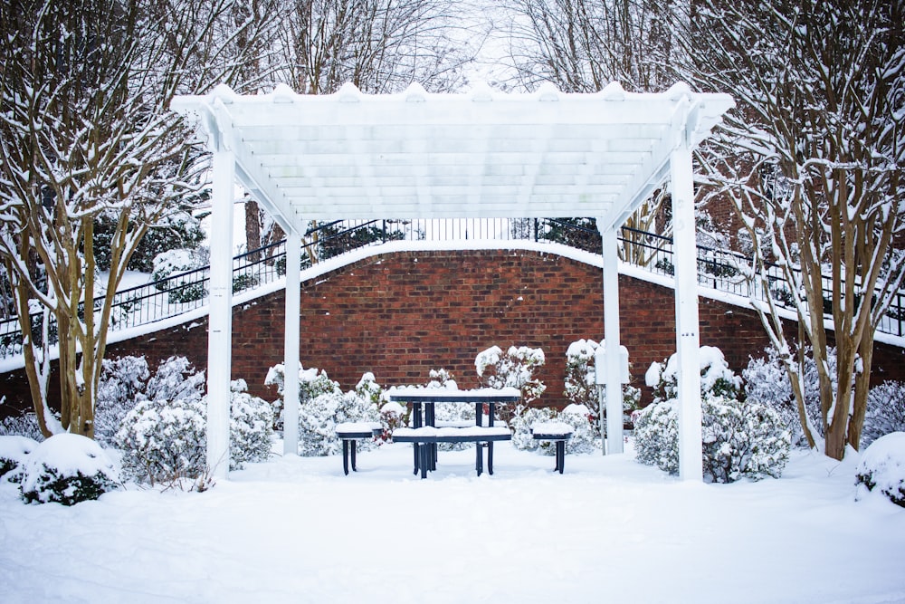 a snow covered park bench under a white canopy