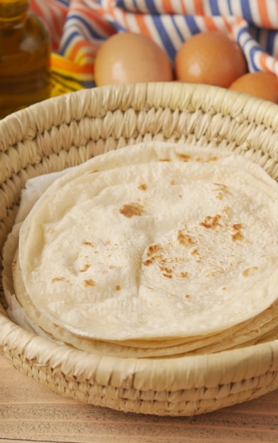 a basket filled with flour next to a bowl of eggs