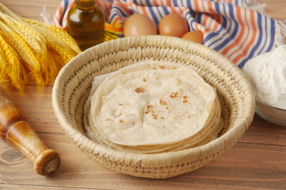 a basket filled with flour next to a bowl of eggs