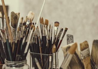 a group of paint brushes sitting in a glass container