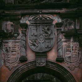 An ancient stone coat of arms carved into a castle wall.