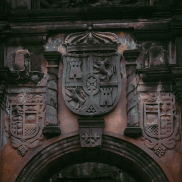An ancient stone coat of arms carved into a castle wall.