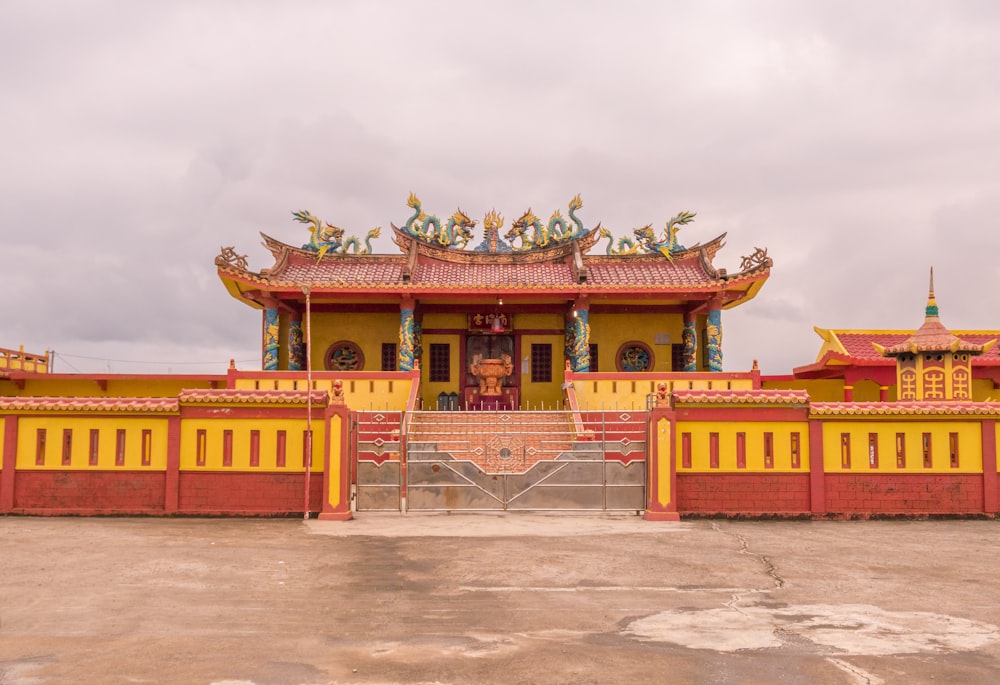 a yellow and red building with statues on top of it