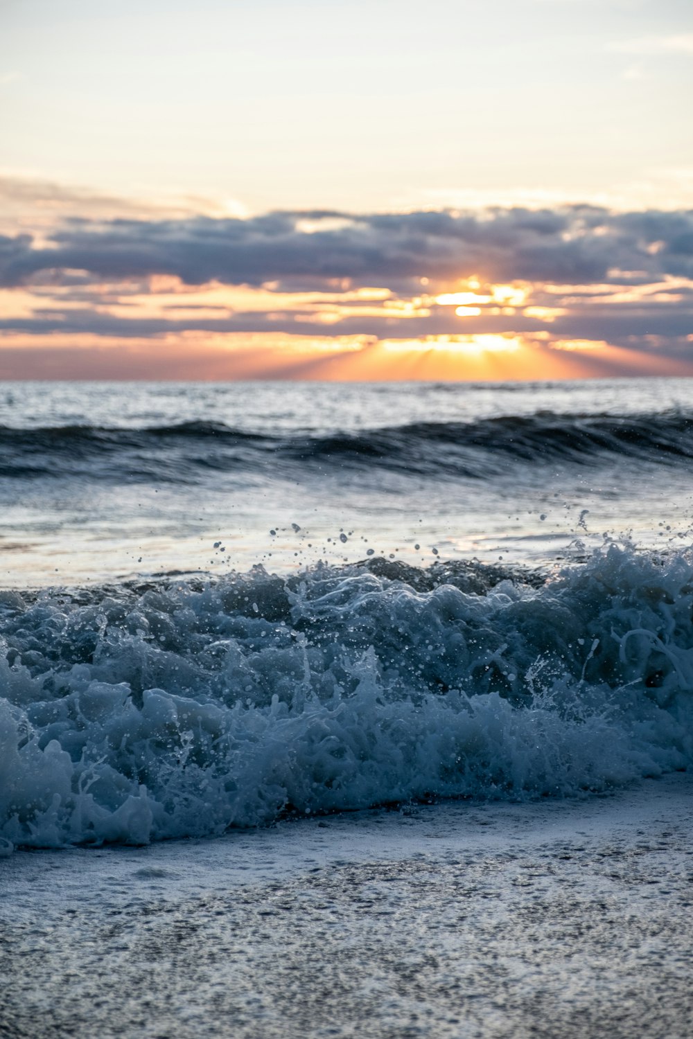 the sun is setting over the ocean waves