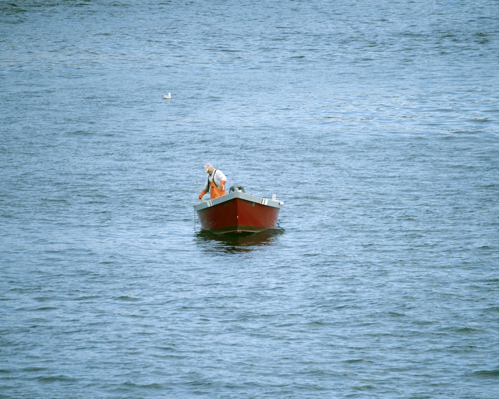 a small red boat floating on top of a large body of water