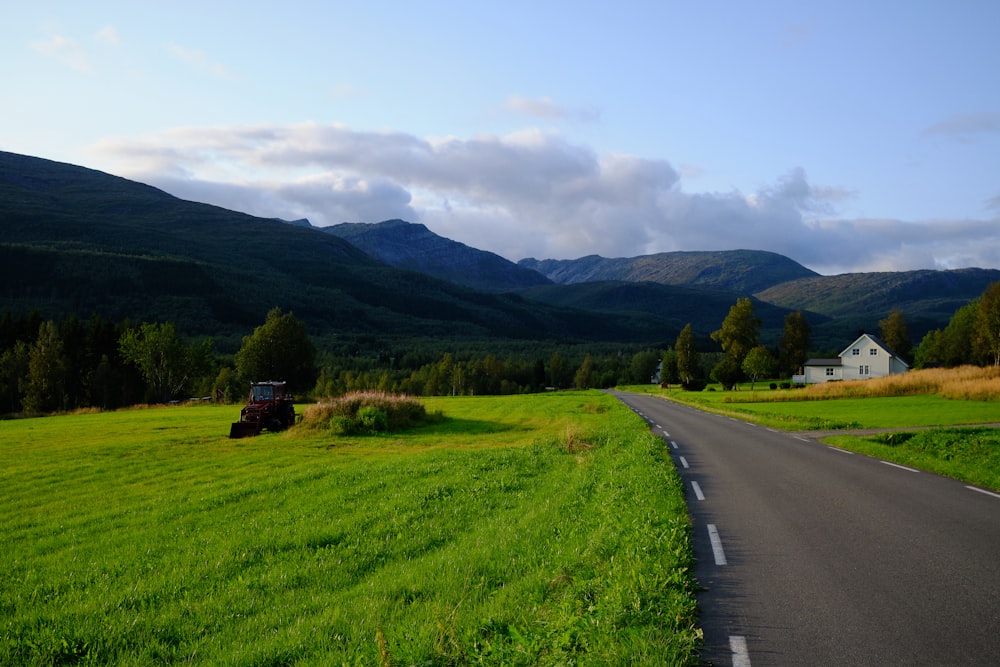 a rural country road with a farm house in the distance