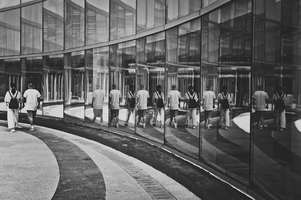 a group of people walking past a glass building