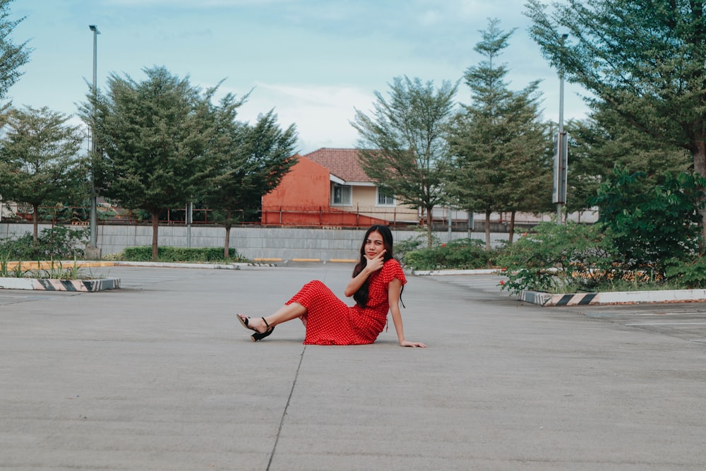 a woman in a red dress sitting on the ground
