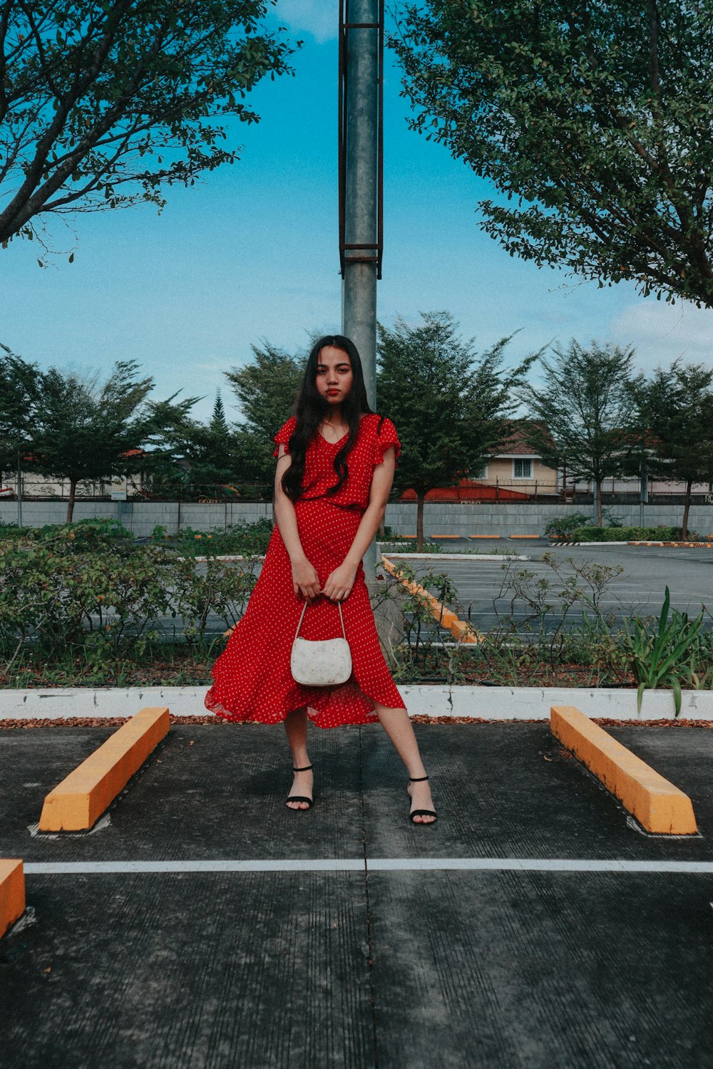 a woman in a red dress standing in a parking lot