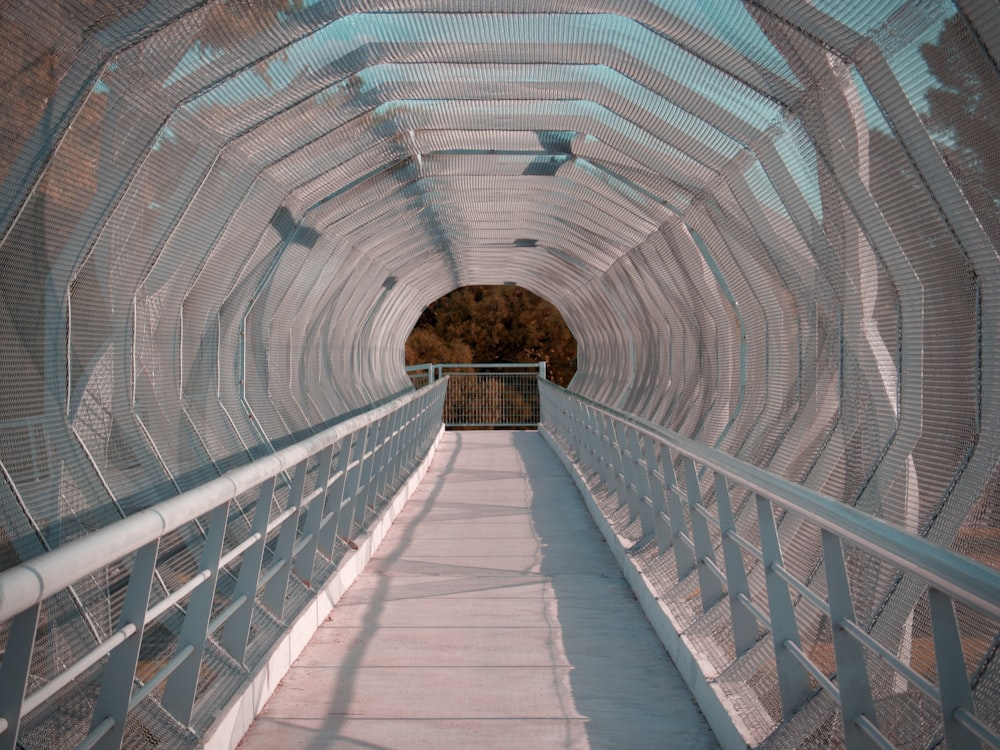 a walkway going through a tunnel with a light at the end