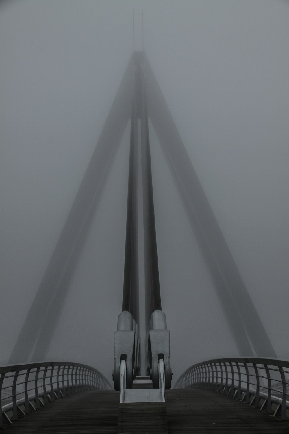 a black and white photo of a bridge in the fog