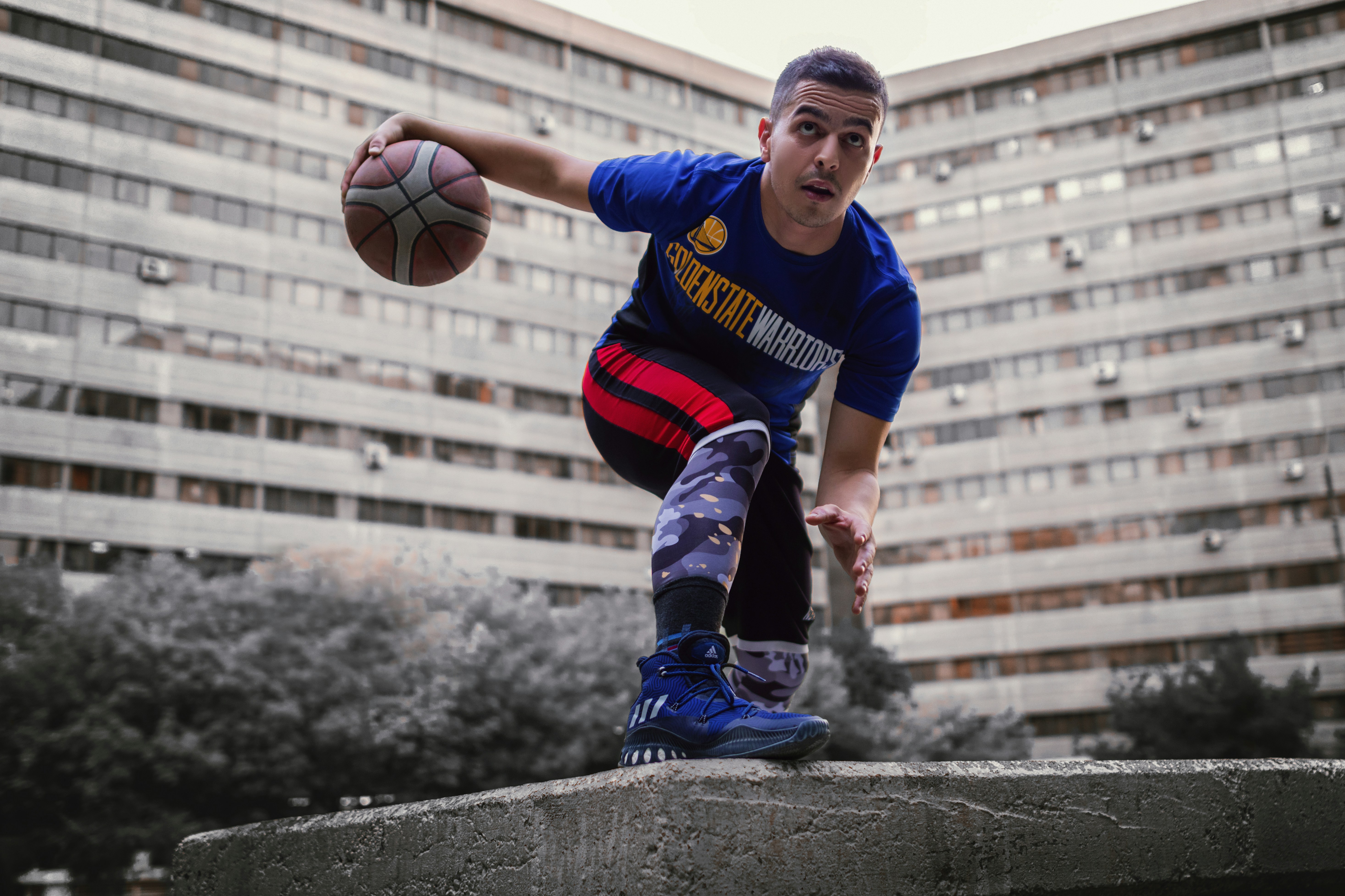 a man holding a basketball on top of a cement block