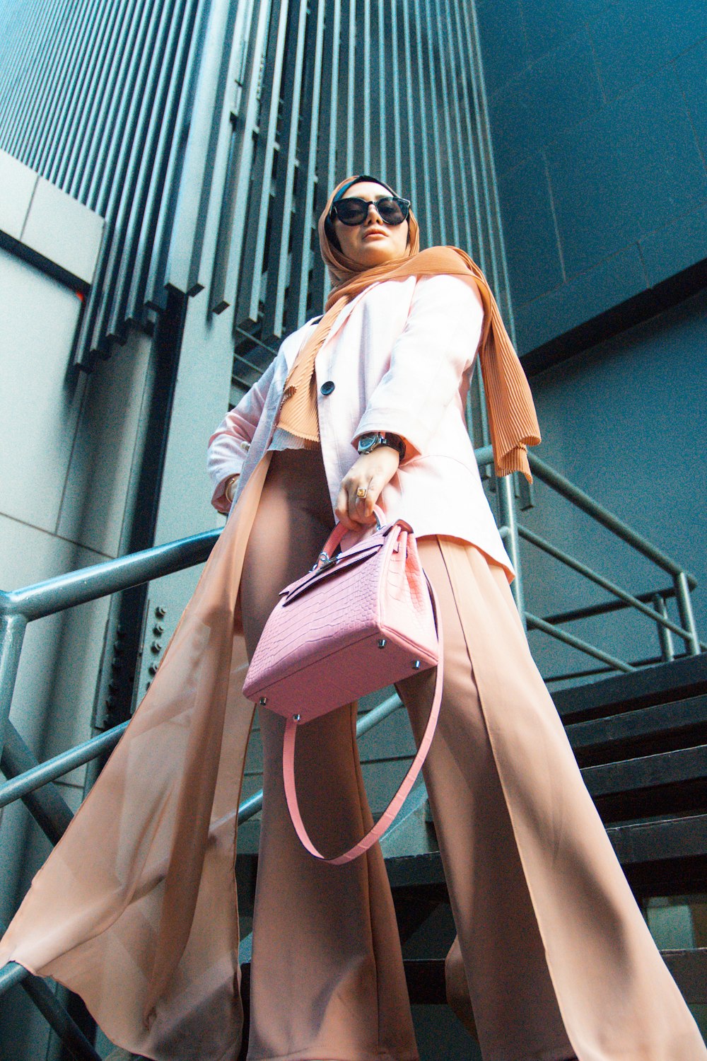 a woman with a pink purse is standing on a stair case