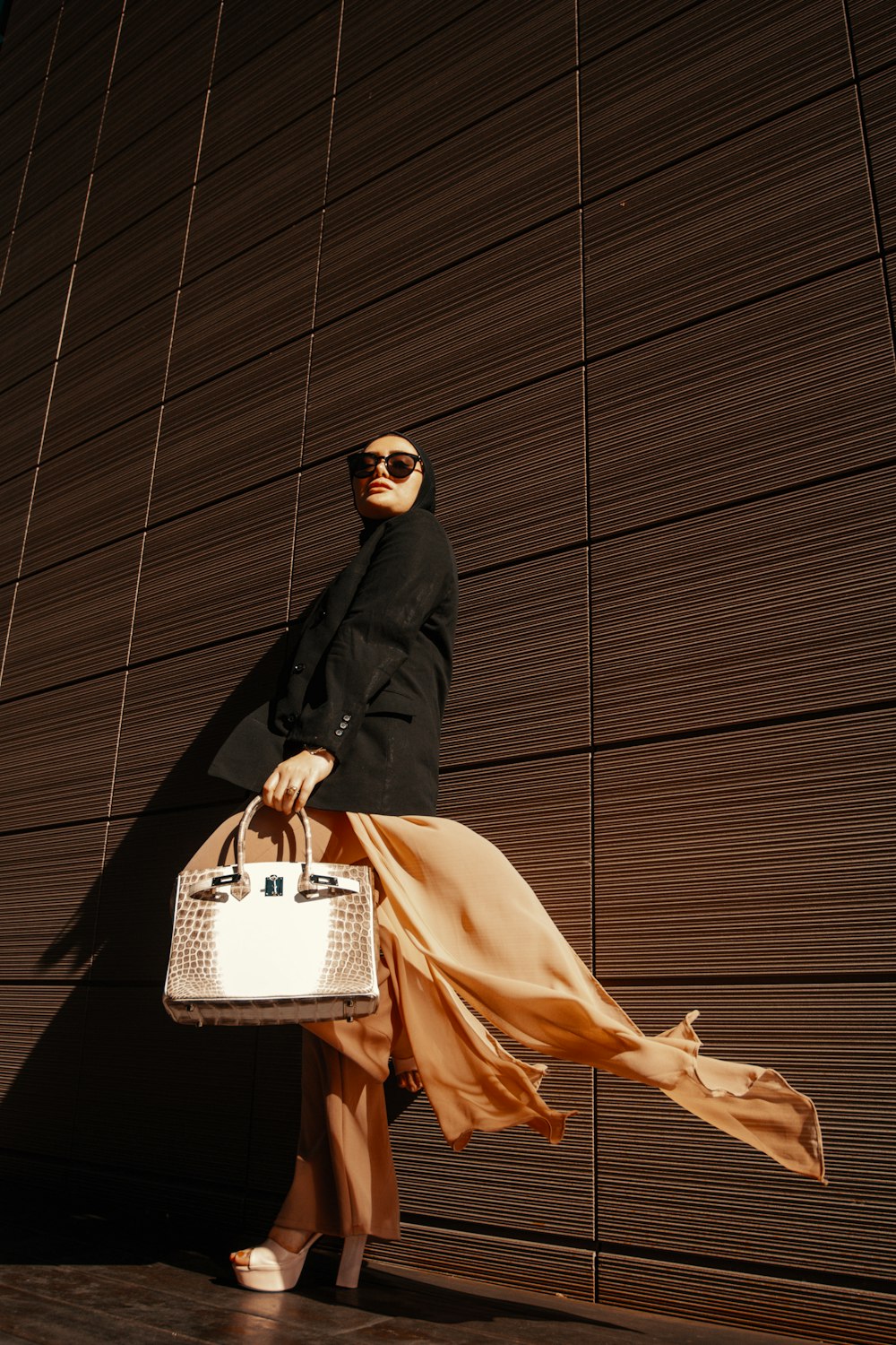 a woman in a black coat carrying a white purse