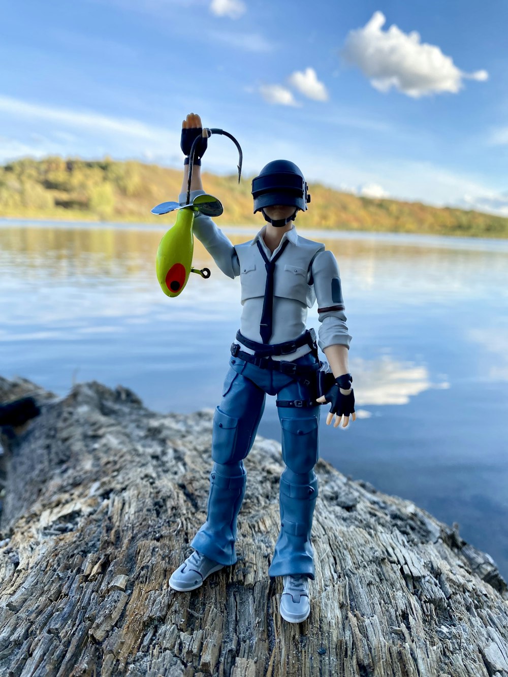 a boy with a helmet and a tie on a rock by a body of water