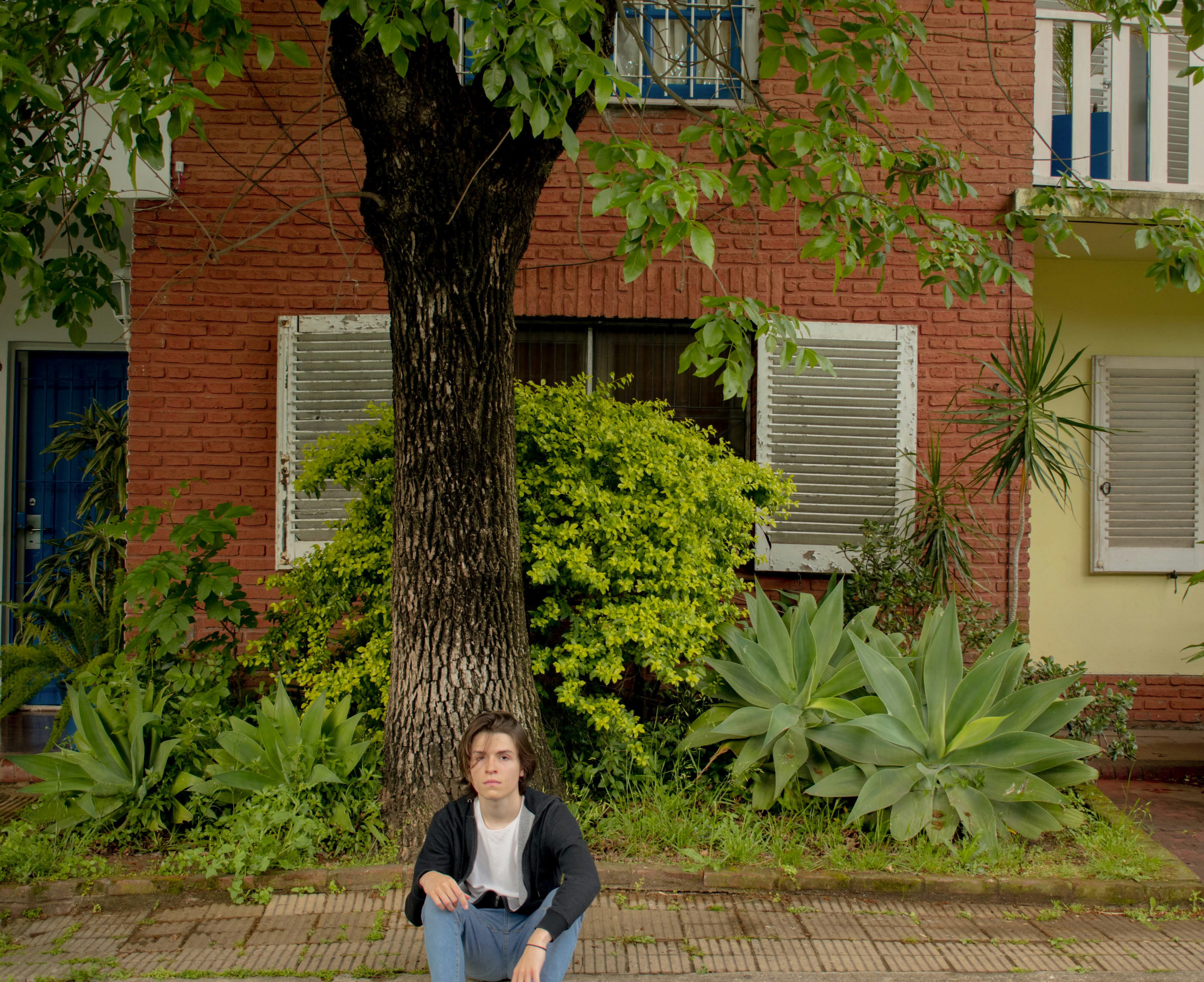 a woman sitting on the ground in front of a tree