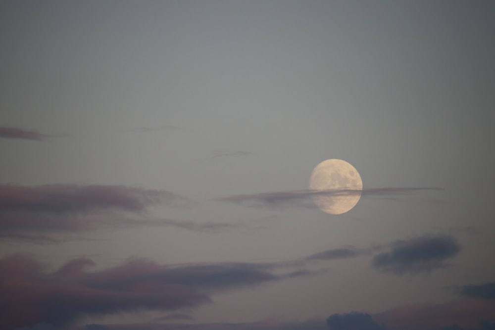 a full moon is seen through the clouds