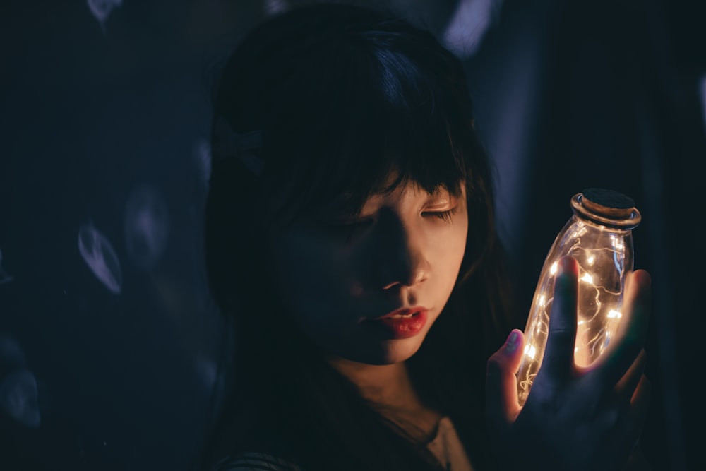 a woman holding a jar with lights in it